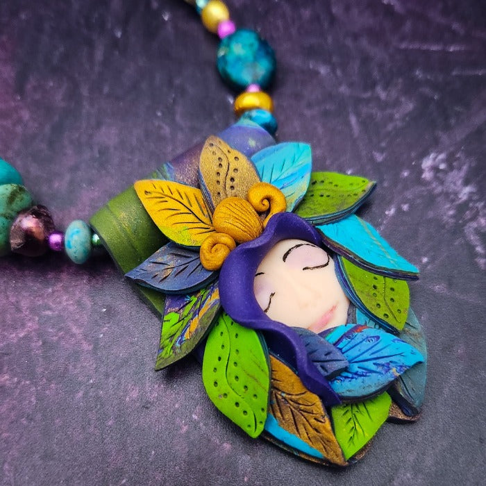 FOREST FAIRIES are ONE OF A KIND Artisan Necklaces. A sweet little fairy is caught napping in her nest of leaves. Each is a one of a kind piece of wearable art with her own unique look and personality. The faces are hand-painted and then surrounded by hand-cut leaves and collected beads, gemstones and sculpted treasures. 