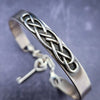 The Cadman Key Keeper Cuff features a chain with a detachable clasp that holds the key to the submissive's lock. With these unique jewelry clasps, the key chain removal is quick and convenient - the key chain can even be linked to a collar during play. Crafted from sterling silver, these luxurious pieces add a sophisticated flair to BDSM boudoirs. By My Secret Heart Studios