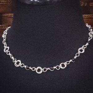 Adorn yourself with this beautiful handcrafted silver and onyx chain that can be transformed into stylish handcuffs and ankle restraints, a chic locking collar, or a gemstone necklace for Dominants. Connect it to the back of a collar for a sexy look, and give a tug on the chain for an extra choking sensation. Includes a Flogger Pendant in sterling silver and a gemstone O Ring Slide with Rose Cut Black Onyx. With its versatile appeal, This CONVERSION CHAIN will certainly be a beloved accessory!