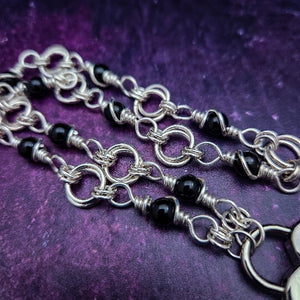 Adorn yourself with this beautiful handcrafted silver and onyx chain that can be transformed into stylish handcuffs and ankle restraints, a chic locking collar, or a decorative necklace for Dominants. Connect it to the back of a collar for a sexy look, and give a tug on the chain for an extra choking sensation. With its versatile appeal, CONVERSION CHAIN, BLACK ONYX & STERLING will certainly be a beloved accessory! By My Secret Heart Studios
