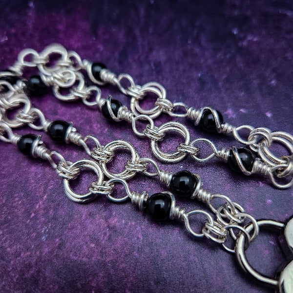 Adorn yourself with this beautiful handcrafted silver and onyx chain that can be transformed into stylish handcuffs and ankle restraints, a chic locking collar, or a decorative necklace for Dominants. Connect it to the back of a collar for a sexy look, and give a tug on the chain for an extra choking sensation. With its versatile appeal, CONVERSION CHAIN, BLACK ONYX & STERLING will certainly be a beloved accessory! By My Secret Heart Studios