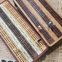 Wooden cribbage boards with pegs on a woven cloth