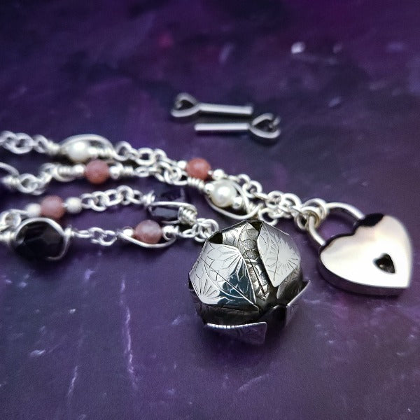 An original, one of a kind design, our locking submissive kitten bell is handcrafted with all the grace and discretion that My Secret Heart is known for. Wear this as a fashion piece or as a subtle submissive or pet play collar, either way you will look amazing!  Crafted in luxurious sterling silver and embellished with pretty pink Rhodochrosite, Amethyst nuggets, pearls and stardust beads, this will make your kitten feel so pretty!  By My Secret Heart Studios