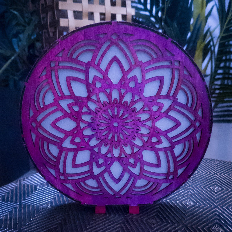 Decorative purple light fixture with intricate geometric pattern on a dark surface.