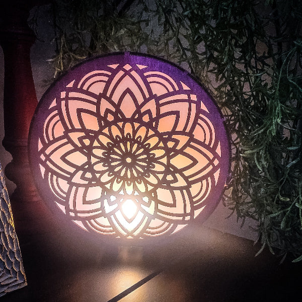 Decorative lantern with intricate pattern emitting a warm glow, surrounded by greenery.