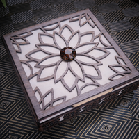 Wooden box with intricate laser-cut design and a central gemstone on a patterned surface.