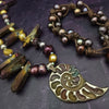 Make a bold statement with MARNIA, the one-of-a-kind necklace featuring titanium druzy, freshwater pearls, and a handcrafted bronze medallion ammonite. Turn heads with the vibrant colors and asymmetrical design, guaranteed to make you look and feel unforgettable!