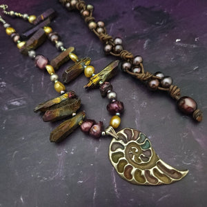 Make a bold statement with MARNIA, the one-of-a-kind necklace featuring titanium druzy, freshwater pearls, and a handcrafted bronze medallion ammonite. Turn heads with the vibrant colors and asymmetrical design, guaranteed to make you look and feel unforgettable!