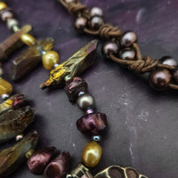 Make a bold statement with MARNIA, the one-of-a-kind necklace featuring titanium druzy, freshwater pearls, and a handcrafted bronze medallion ammonite. Turn heads with the vibrant colors and asymmetrical design, guaranteed to make you look and feel unforgettable!