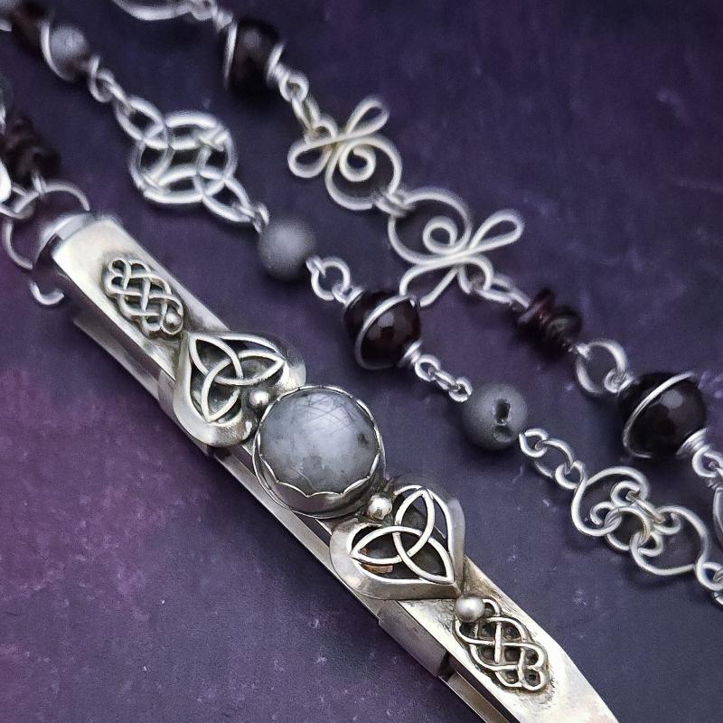 This CELTIC PRIESTESS CAGE features a large, hard to find Silver Star Sapphire and is embellished with Celtic Hearts and Celtic Knot accents. Measures approx. 4" long.&nbsp;

THE ARTISAN CHAIN is asymetrical and features incredible faceted garnets and grey druzies, all wrapped in sterling silver. The handcrafted links make this a true artisan piece you'll treasure for years. Hefty weight. Silver Star Sapphire, Garnets and Grey Druzy, One of a Kind by My Secret Heart Studios