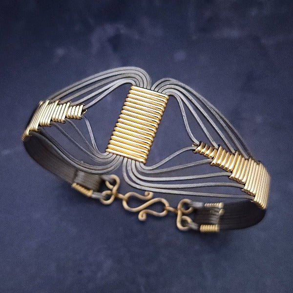 A modern twist on classic royalty, the CLEO Locking Cuff Bracelet is a bold yet discreet tribute to the powerful Egyptian Queen. Wrapped in titanium and accented with 14K gold filled details, it's an alluring and timeless statement piece.