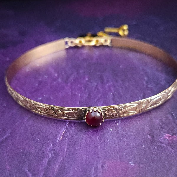 Our Soft and Sweet submissive collar is the epitome of feminine grace. Handcrafted with loving care, this artisan-made 14k gold filled submissive collar radiates femininity with its floral sterling silver pattern and a hand-set 8mm Garnet. Beautifully feminine and romantic.