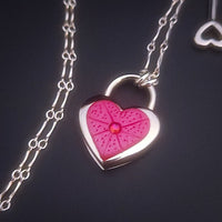 Revamp your locks with a touch of style. This locking soft chain collars features a small heart lock, adorned with a vibrant pink burst pattern and a sparkling center crystal. The embellished lock can also be worn with other collars and chains. Strut your ownership/submission in style ... never wear a plain ole' lock again!!