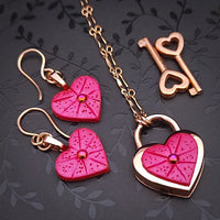 Revamp your locks with a touch of style. This locking soft chain collars features a small heart lock, adorned with a vibrant pink burst pattern and a sparkling center crystal. The embellished lock can also be worn with other collars and chains. Strut your ownership/submission in style ... never wear a plain ole' lock again!!