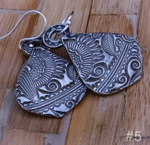 Each pair is created from a lump of cold grey clay that contains microscopic particles of fine silver. Hilly rolls the clay thin, adds a texture, and then meticulously pairs the textures so they are true companion pieces. She even embellishes the back.