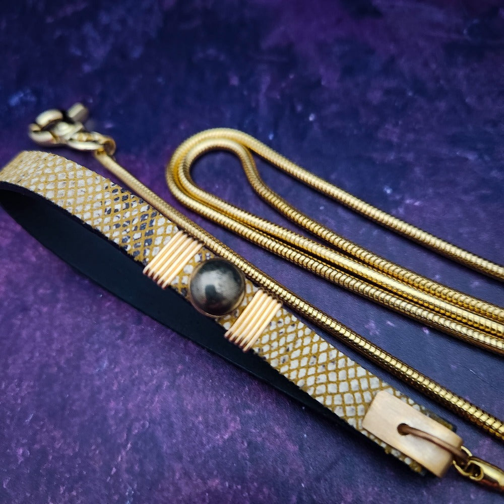 Luxurious BDSM leash for that special time or event. The Golden Snakeskin Leather is accented gold wire wraps and features an earthy toned natural Pyrite gemstone. Riveted for strength. The 35 inch golden brass snake chain is slinky with a sensual feel.  A swivel trigger clip moves with you both for great mobility. This is uber-sexy! My Secret Heart Studios