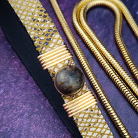 Luxurious BDSM leash for that special time or event. The Golden Snakeskin Leather is accented gold wire wraps and features an earthy toned natural Pyrite gemstone. Riveted for strength. The 35 inch golden brass snake chain is slinky with a sensual feel.  A swivel trigger clip moves with you both for great mobility. This is uber-sexy! My Secret Heart Studios