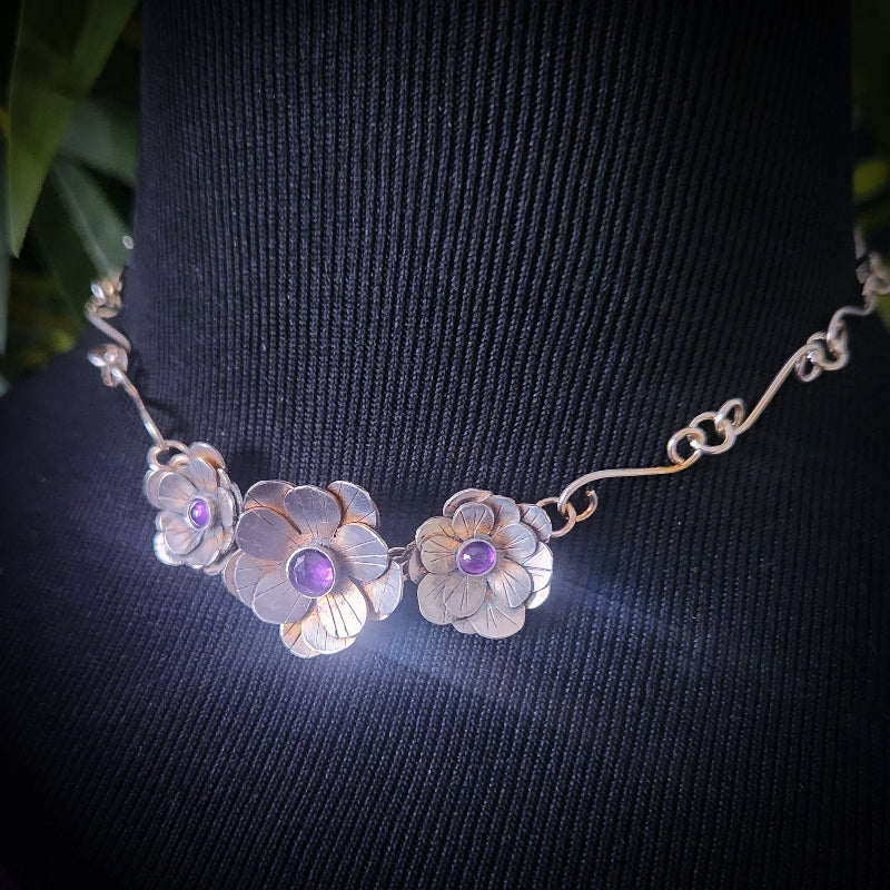 Aphrodite Flower Collar with purple stones on a black background 