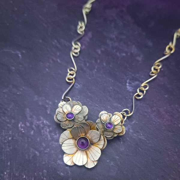 Floral necklace with purple stones on a textured purple background