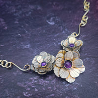 Floral jewelry piece with purple stones on a dark textured background