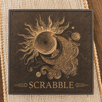 A Celestial engraved Scrabble Game Set featuring an engraved celestial design with a sun, crescent moon, planets, and the word 'SCRABBLE' at the bottom.