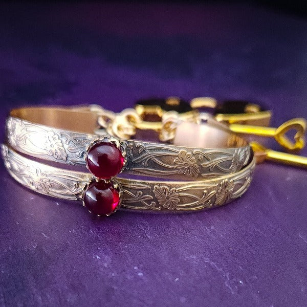 Show your ownership or submission with style and grace. Our best selling ‘SOFT and SWEET’ Locking BDSM submissive handcuff bracelets are now available in anklets sizes as well. These artisan handcuffs / ankle restraints are hand crafted in a pretty feminine floral pattern of 14kGold-Fille and natural Garnet. The epitome of feminine grace. 