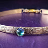 Our NEW Gold & Azotic Galazio Blue Topaz. Soft and Sweet submissive collar and cuffs are the epitome of feminine grace. Handcrafted with loving care, these artisan-made 14k gold filled submissive collars and cuffs radiate femininity with a floral pattern and a hand-set 8mm Azotic Galazio Blue Topaz. Beautifully feminine and romantic.