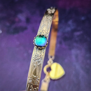 Our Soft and Sweet submissive collar is the epitome of feminine grace. Handcrafted with loving care, this artisan-made 14k gold filled submissive collar radiates femininity with its floral sterling silver pattern and a hand-set 8mm Azotic Galazio Blue Topaz. Beautifully feminine and romantic.