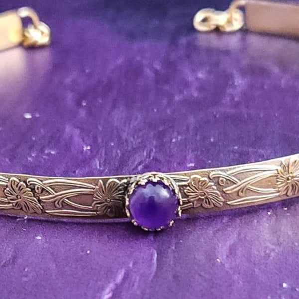 Our NEW GOLD & AMETHYST Soft and Sweet submissive collar and cuffs are the epitome of feminine grace. Handcrafted with loving care, these artisan-made 14k gold filled submissive collars and cuffs radiate femininity with a floral pattern and a hand-set 8mm Natural Amethyst. Beautifully feminine and romantic.