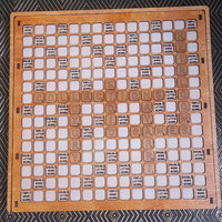 A wooden Scrabble board with white square tiles and engraved letter tiles, photographed from above on a dark patterned fabric background.