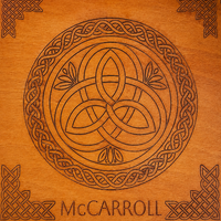 A square wooden plaque or box cover featuring a carved Celtic knot design with a central triquetra-like symbol inside a circular border, corner knot motifs, and the name 'McCARROLL' at the bottom.