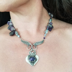 Wear the Velavee Angel Necklace and radiate your inner goddess! Crafted from sterling silver and the rare gemstone Charoite, this one-of-a-kind necklace is adorned with angel wing and a inverted fan shaped medallion, creating a beautiful and unique statement. By My Secret Heart Studios