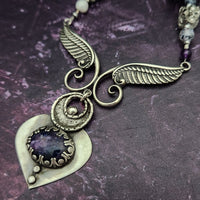 Wear the Velavee Angel Necklace and radiate your inner goddess! Crafted from sterling silver and the rare gemstone Charoite, this one-of-a-kind necklace is adorned with angel wing and a inverted fan shaped medallion, creating a beautiful and unique statement. 