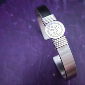 The substantial weight of this sterling cuff lends this a sense of gravitas, while an engraved BDSM symbol is nestled between silver wraps. The simplistic design makes it a perfect companion for almost any other jewelry in your collection.  