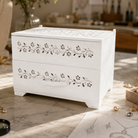 White jewelry box with floral patterns on a marble surface with jewelry-making tools and materials.