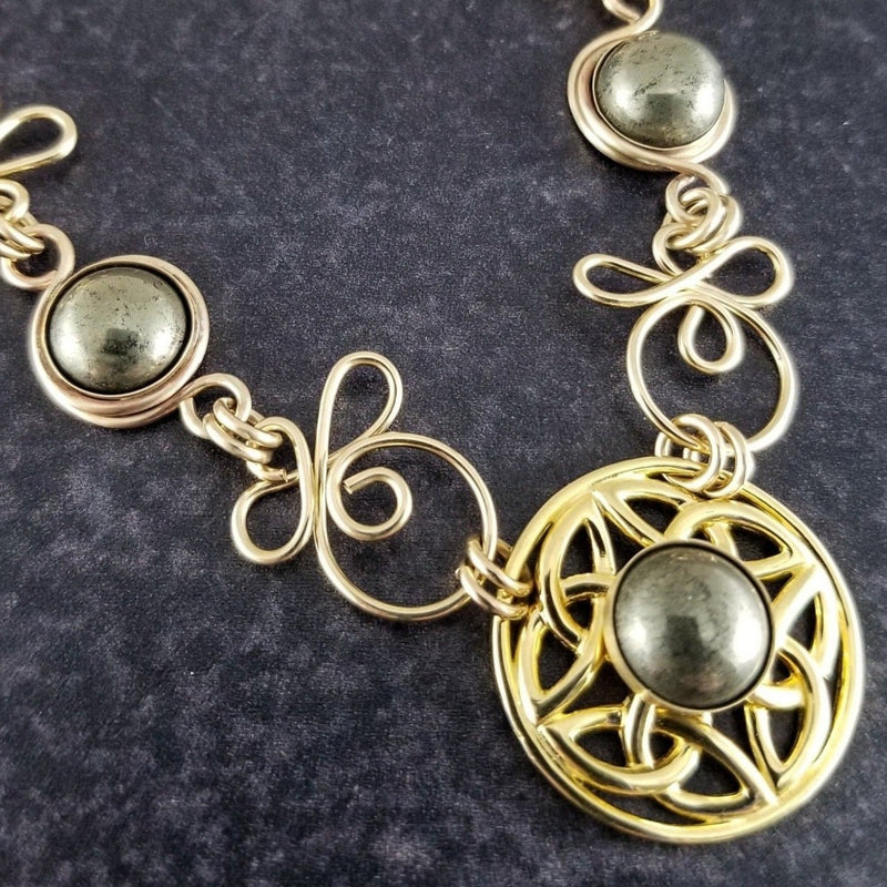 The Celtic Priestess Triquetra Medallion Collar features chain links inspired by Celtic knots, all created entirely by hand using only a few hand tools. The links are then tumbled with steel shot, creating strength and durability, as well as a silky smoothness.   The center medallion is a gold plated Celtic Triquetra Knot set with natural Pyrite. My Secret Heart Studios