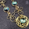 Features chain links inspired by Celtic knots, all created entirely by hand using only a few hand tools. The links are then tumbled with steel shot, creating strength and durability, as well as a silky smoothness.   The center medallion is a gold plated Celtic Triquetra Knot set with natural Rainbow Topaz. By My Secret Heart Studios. 