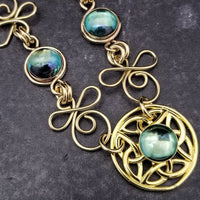 Features chain links inspired by Celtic knots, all created entirely by hand using only a few hand tools. The links are then tumbled with steel shot, creating strength and durability, as well as a silky smoothness.   The center medallion is a gold plated Celtic Triquetra Knot set with natural Rainbow Topaz. By My Secret Heart Studios. 