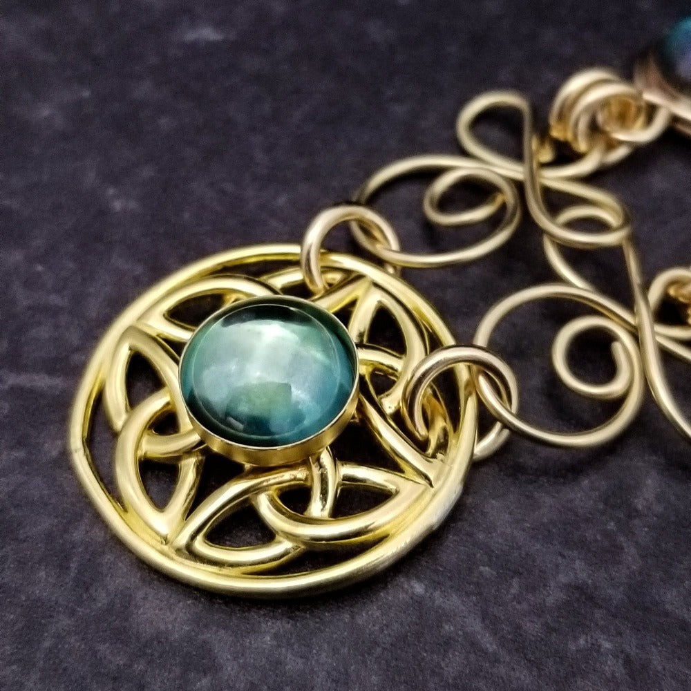 Features chain links inspired by Celtic knots, all created entirely by hand using only a few hand tools. The links are then tumbled with steel shot, creating strength and durability, as well as a silky smoothness.   The center medallion is a gold plated Celtic Triquetra Knot set with natural Rainbow Topaz. By My Secret Heart Studios.