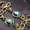 Features chain links inspired by Celtic knots, all created entirely by hand using only a few hand tools. The links are then tumbled with steel shot, creating strength and durability, as well as a silky smoothness.   The center medallion is a gold plated Celtic Triquetra Knot set with natural Rainbow Topaz. By My Secret Heart Studios.
