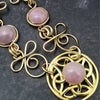 The Celtic Priestess Triquetra Medallion Collar features chain links inspired by Celtic knots, all created entirely by hand using only a few hand tools. The links are then tumbled with steel shot, creating strength and durability, as well as a silky smoothness.   The center medallion is a gold plated Celtic Triquetra Knot set with natural Kunzite. My Secret Heart Studios
