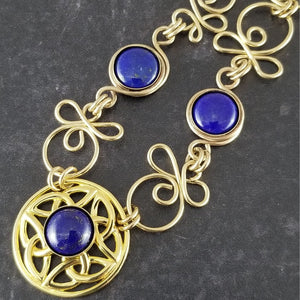 Features chain links inspired by Celtic knots, all created entirely by hand using only a few hand tools. The links are then tumbled with steel shot, creating strength and durability, as well as a silky smoothness.   The center medallion is a gold plated Celtic Triquetra Knot set with natural Lapis Lazuli. My Secret Heart Studios.