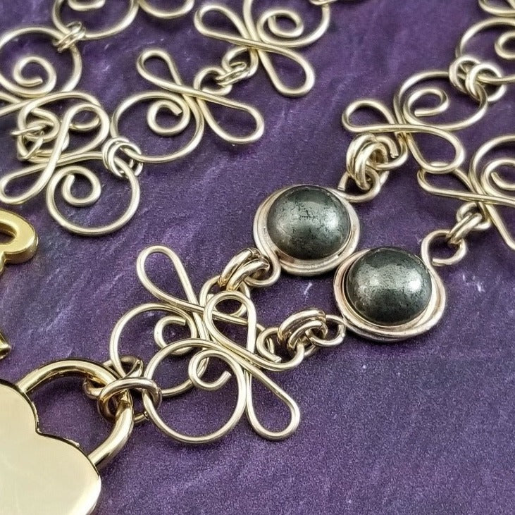 Made a bold statement of your Dominant / submissive lifestyle. The CELTIC PRIESTESS locking submissive collar features chain links inspired by Celtic knots, all created entirely by hand. Embellished with 2 natural gemstone cabochons of your choice.