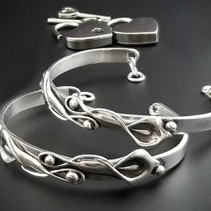 The Calla Lily Handcuff bracelets are a graceful addition to our artisan BDSM jewelry collection. Your submissive is sure to love this feminine and elegant locking cuff. Made in solid sterling silver, with a few links of chain to create a comfortable, 'movable' fit, even when locked. Total discretion!