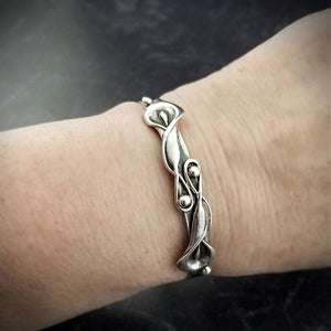 The Calla Lily Handcuff bracelets are a graceful addition to our artisan BDSM jewelry collection. Your submissive is sure to love this feminine and elegant locking cuff. Made in solid sterling silver, with a few links of chain to create a comfortable, 'movable' fit, even when locked. Total discretio
