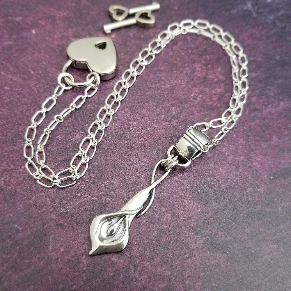 Nature Inspired. Graceful and timeless. This locking submissive BDSM soft collar is the epitome of discretion. The Calla Lily hangs from a sterling chain, but can be removed and slipped onto several of our MSHS submissive collars. Or the 'slide' can also be worn on chains, leather, ribbon, etc. Three versions available: Traditional, Permanently Locking or Lock and Key.