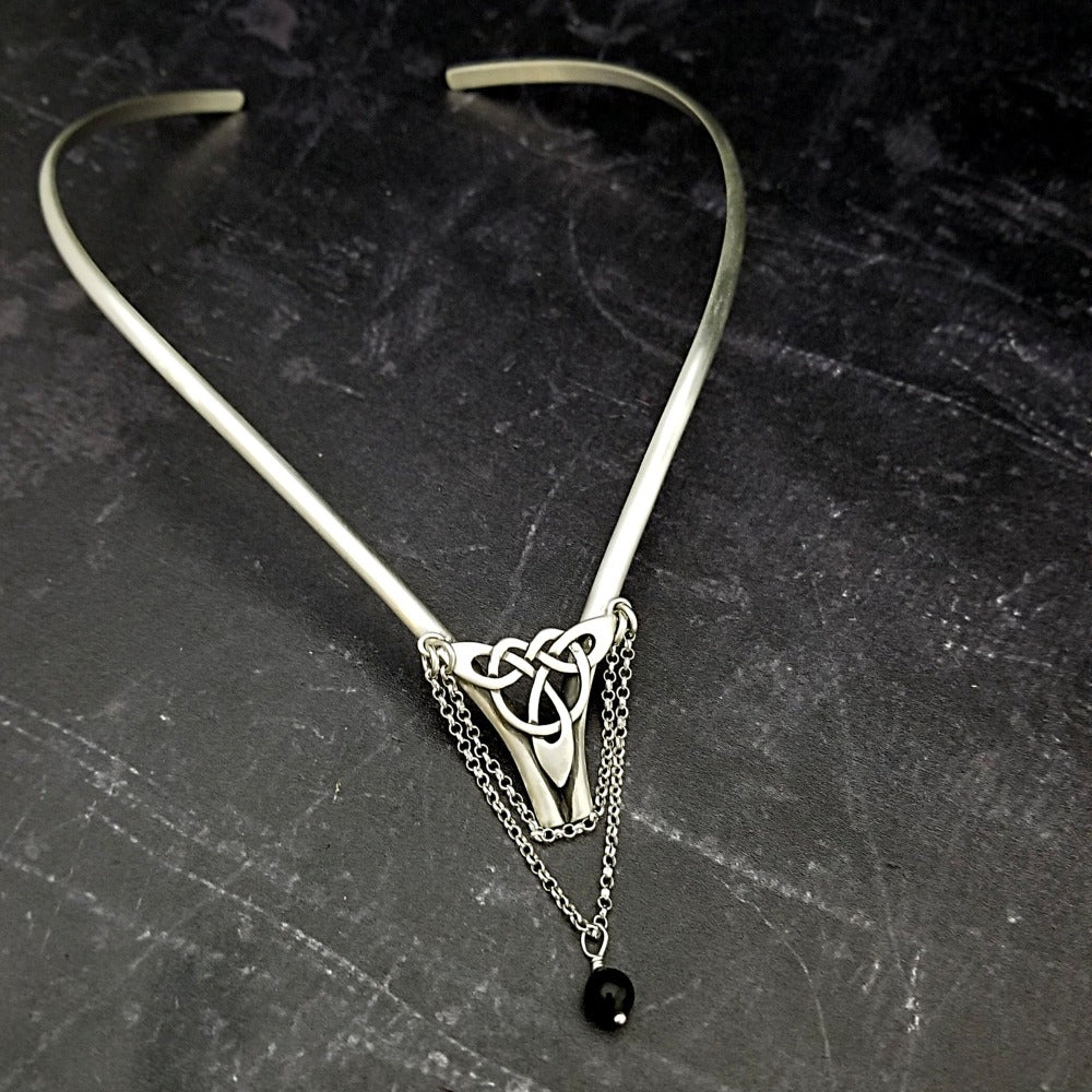Inspired by campfires, music and moonlight dancing. Ancient past, present and future. Substantial open back style collar has a nice fluid curve that hugs the neck. Celtic knot with swag chain and black onyx bead. Created in all luxurious sterling silver, its solid, weighty construction makes it a timeless piece that you'll be able to enjoy for years to come. My Secret Heart Studios