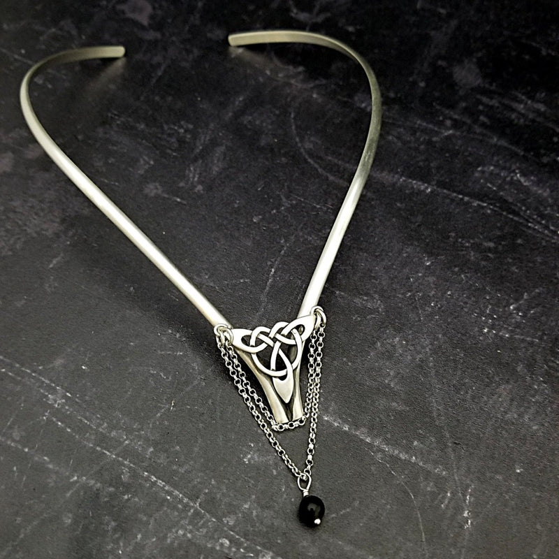 Inspired by campfires, music and moonlight dancing. Ancient past, present and future. Substantial open back style collar has a nice fluid curve that hugs the neck. Celtic knot with swag chain and black onyx bead. Created in all luxurious sterling silver, its solid, weighty construction makes it a timeless piece that you'll be able to enjoy for years to come. My Secret Heart Studios
