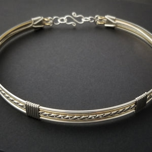 Sterling submissive collar that is discreet for daytime, yet kinky for playtime. The Celtic inspired design features a rope pattern, with accent lines of sterling and 14k gold filled, all wrapped together with sterling wraps. 