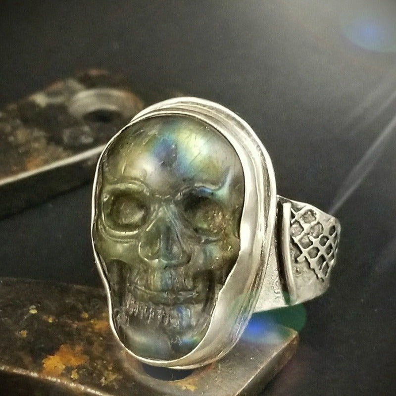 This skull ring features a hand carved labradorite skull, set into a fine silver bezel.  The band is created to look old and organic.